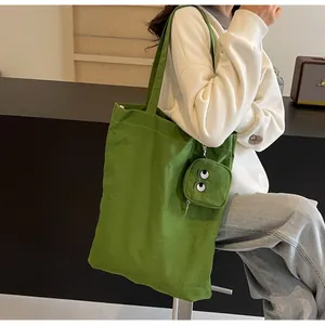 Detail of vibrant green tote bag with monster eyes embroidery and mini charm pouch