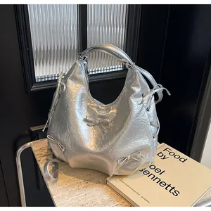Detail of silver metallic tote bag featuring wrinkled mirror leather and ribbon accents