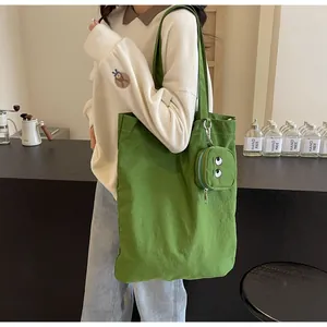 Detail of green canvas tote bag with embroidered eye mini pouch in a cozy cafe setting