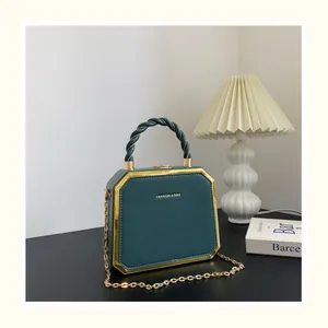Détail du sac octogonal en cuir vert foncé avec garniture dorée et poignée tressée