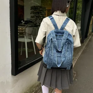 Vintage dark blue denim backpack with stitch details shown on model in urban street setting