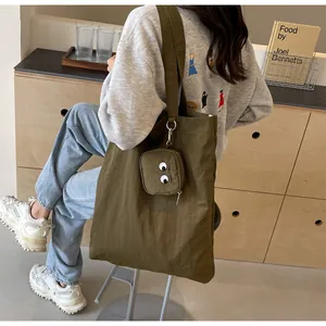 Detailed close-up of olive green tote bag with cute monster mini pouch accessory