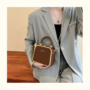 Détail d'un sac hexagonal marron en cuir avec cadre doré et logo de mode chic