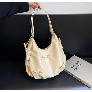 Detail of cream hobo bag featuring crinkled leather texture and delicate bow accents