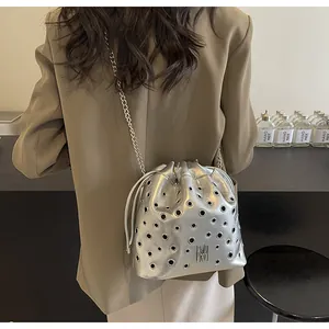 Vue détaillée du sac seau argenté avec oillets métalliques et logo M décoratif