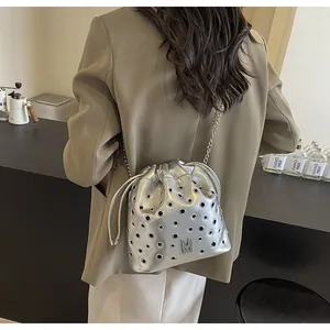 Détail du sac seau argenté avec œillets métalliques et une bandoulière en chaîne