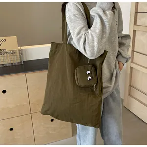 Detail of olive canvas tote bag with embroidered eye charm and adjustable shoulder strap