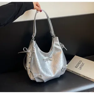 Close-up of silver Hobo bag with metallic pleated fabric and bow ribbon details