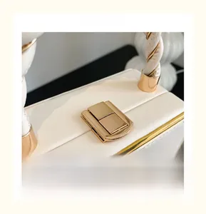 Détail du sac en cuir grainé blanc avec fermoir doré et poignée tressée élégante