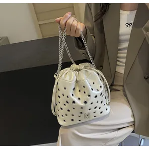 Détail du sac seau crème à cordon avec œillets argentés et bandoulière en chaîne