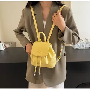 Detail of yellow mini leather backpack with magnetic flap closure and drawstring design