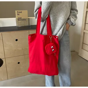 Detail of red canvas tote bag with a small cartoon eye embroidery pouch attached