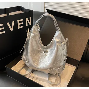 Detail of silver metallic tote bag featuring 3D bow accents and stylish pleated texture