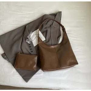 Détail du sac hobo en cuir marron foncé et de sa pochette assortie avec boucles dorées