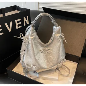 Detail of silver metallic tote with bow accents and crinkled texture in a gift box