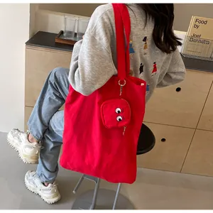 Detail of red canvas tote bag with cute cartoon eye embroidery and matching small pouch
