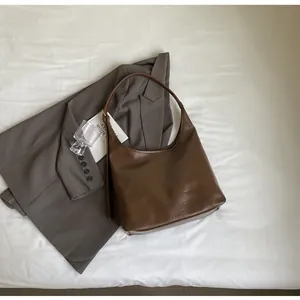 Détail du sac Hobo marron foncé avec texture plissée naturelle et bandoulière mince