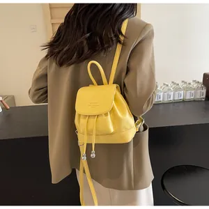 Detail of yellow soft leather mini backpack featuring drawstring and embossed brand text