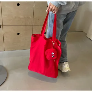 Close-up of red canvas tote bag with monster eye charm and matching mini pouch