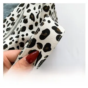 Détail de la bandoulière en toile d'un sac cabas à imprimé léopard noir et blanc