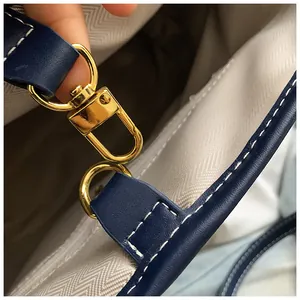 Détails du fermoir doré et des surpiqûres blanches sur le sac fourre-tout en cuir bleu