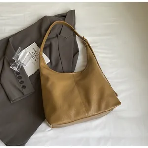 Détail du sac fourre-tout plissé marron kaki avec bandoulière sur fond de costume gris