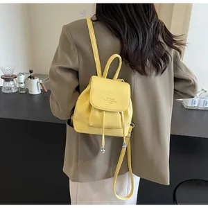 Detail showing bright yellow textured leather mini backpack with drawstring and silver hardware