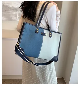 Detail of denim patchwork tote bag featuring contrast colors and wide fabric strap