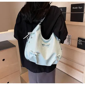 Detail of light blue hobo bag with ribbon bows and stylish drawstring texture
