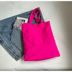 Close-up of vibrant neon pink embroidered tote bag on a denim jacket and white background