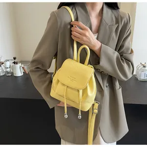 Detail of a bright yellow mini leather backpack featuring silver sphere pendant and flap closure