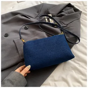 Détail du sac cabas en denim bleu avec crochets dorés sur fond de blazer gris