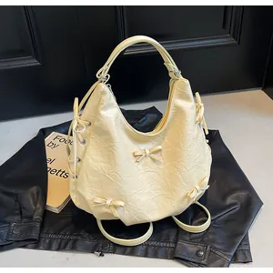 Detail of cream hobo bag featuring decorative bows and natural wrinkled texture fabric