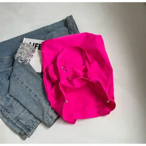 Flat lay of pink canvas tote bag with a small monster eye zipper pouch and blue denim jacket