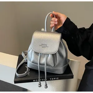 Close-up of metallic silver mini backpack featuring soft litchi texture and drawstring detail