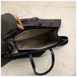 Deep blue tote bag featuring white contrast stitching and a spacious inner zip pocket