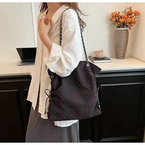 Detail of black tote bag with red heart patterns and silver chain shoulder strap