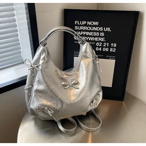 Silver metallic pleated hobo bag featuring decorative bows and industrial texture