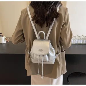 Silver mini bucket backpack with pebble leather texture and metal finish on a model