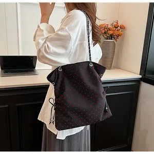 Black canvas tote bag featuring red heart patterns and silver chain strap detail