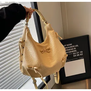 Detail of cream pleated tote bag featuring delicate bow accents and textured faux leather
