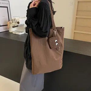 Brown nylon tote bag with cartoon eye charm and large capacity for daily use