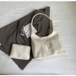 Vue détaillée du sac cabas crème texturé et de sa petite pochette zippée assortie