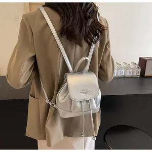 Rear view of model wearing a mini silver backpack with pebbled leather texture