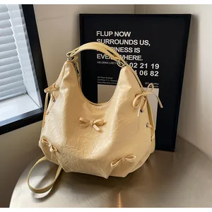 Detail of cream yellow pleated tote bag with bow accents and soft PU leather texture