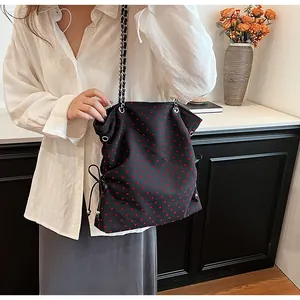 Detail of black heart print tote bag with chain strap and adjustable side drawstring