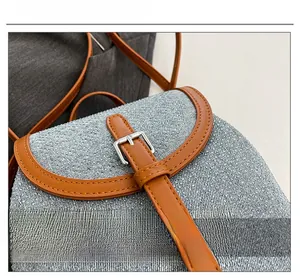 Close-up of blue textured woven fabric with brown faux leather strap and metal buckle
