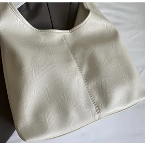 Détails de la texture plissée et des coutures sur un grand sac cabas couleur crème