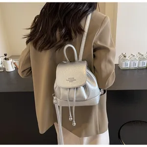 Silver metallic leather mini backpack detail showing embossed logo and drawstring closure