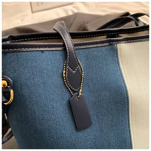 Détails rapprochés du sac cabas en denim avec coutures contrastées et métal doré